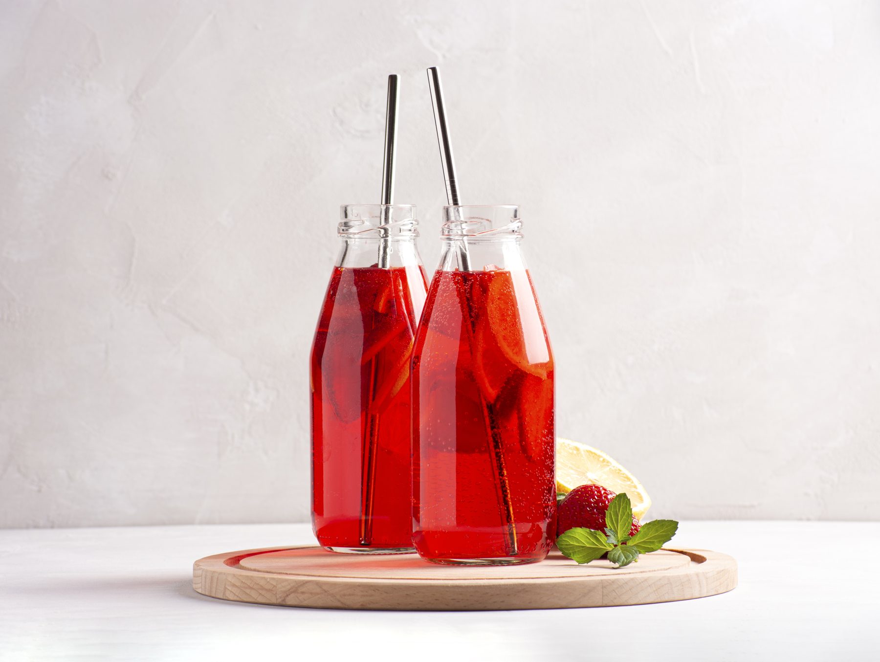 Dos botellas de agua de jamaica con hielo y fresas
